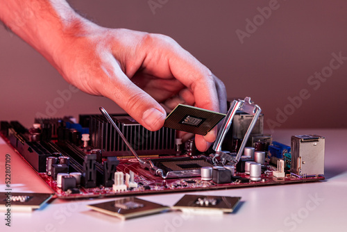 A man's hand inserts a processor into the motherboard chipset