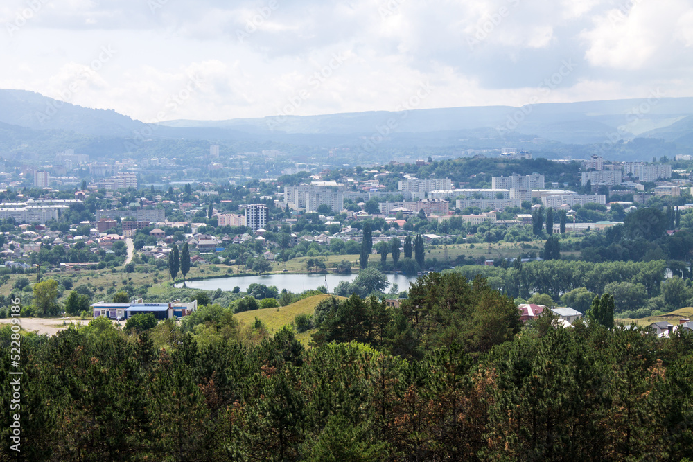 Panoramic top view of the city of Kislovodsk in Russia with green trees and architecture through a misty haze on a sunny summer day and a sky with clouds