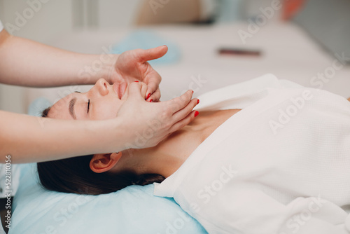 Beautiful young woman getting face skin treatment massage at beauty spa