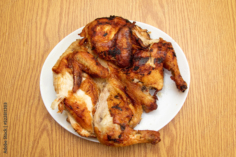 Whole fried chicken on a plate on a wooden table Whole fried chicken on a plate on a wooden table