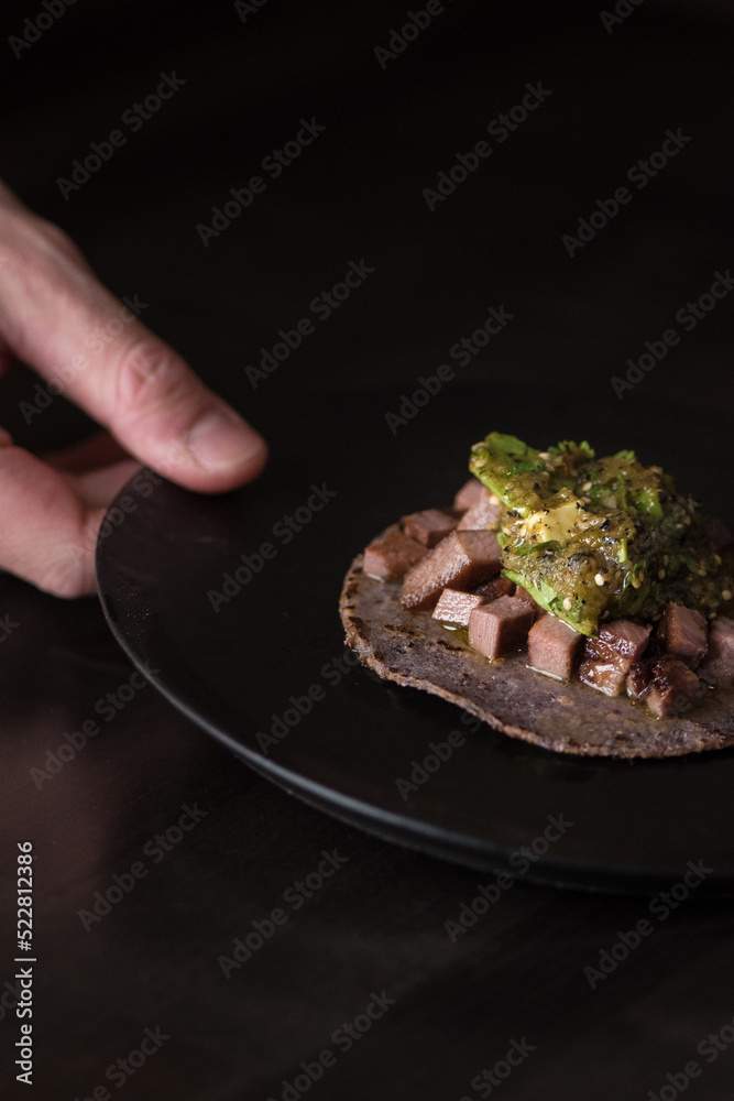 hand holding a dish with a cow tongue taco hand holding a dish with a cow tongue taco