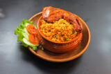 Chicken matka biryani with salad served in a matka isolated on dark background side view of indian spicy food
