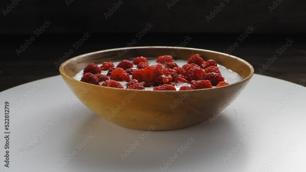 Fresh raspberries in cream in a wooden plate rotation in a circle. Medium plan Fresh raspberries in cream in a wooden plate rotation in a circle. Medium plan