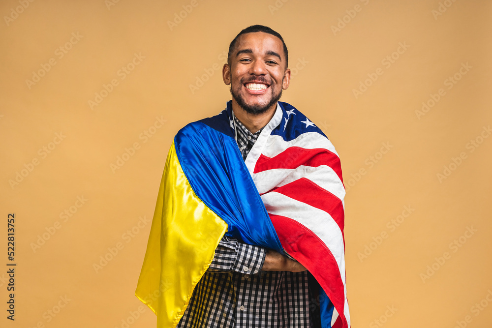© denis_vermenko - Portrait of positive african american black guy holding usa and ukrainian flags, isolated over beige background. © denis_vermenko - Portrait of positive african american black guy holding usa and ukrainian flags, isolated over beige background.