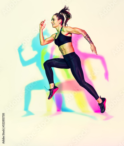 Sporty woman runner in silhouette. Photo of muscular woman in black sportswear on white background with effect of rgb colors shadows. Dynamic movement. Side view. Sport and healthy lifestyle