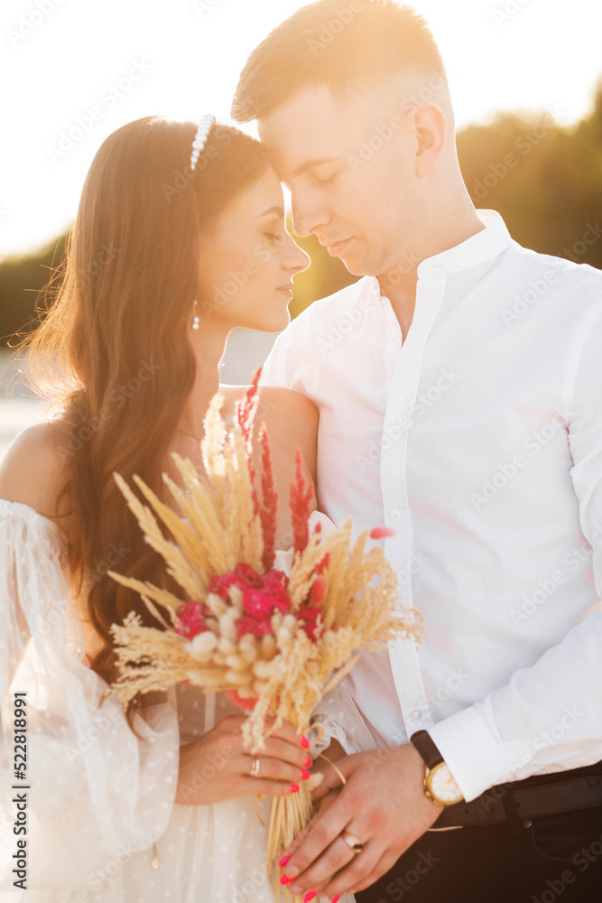 A girl in a white dress ivory shade. A loving couple is embracing tenderly against the background of white sand at sunset A girl in a white dress ivory shade. A loving couple is embracing tenderly against the background of white sand at sunset