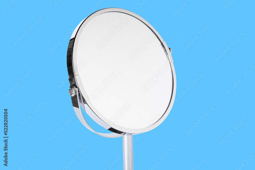 Desktop make up cosmetic mirror isolated on blue background. Home metal mirror close up isolated. Facial mirror.