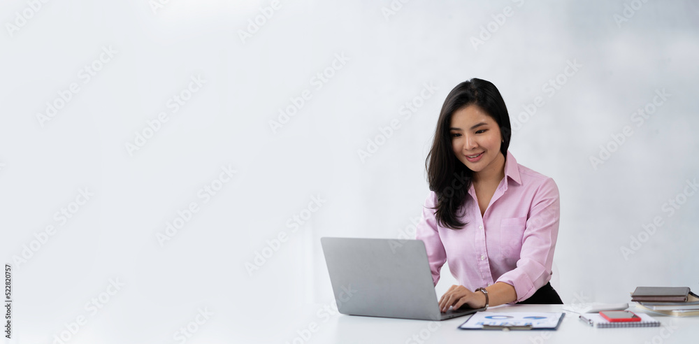 Attractive Asian businesswoman sitting happily smiling and working on her laptop in the office. Attractive Asian businesswoman sitting happily smiling and working on her laptop in the office.