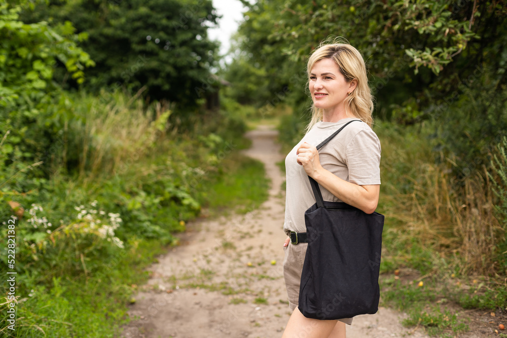 consumerism, eating and eco friendly concept - woman with reusable canvas bag for food shopping over green natural background consumerism, eating and eco friendly concept - woman with reusable canvas bag for food shopping over green natural background