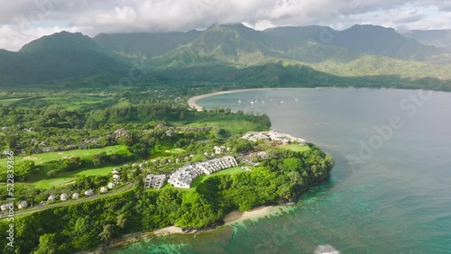 Cinematic Princeville shore with summer beach cottages and oceanfront villas on scenic Hawaii landscape background. Summer vacation in paradise 4K drone. Aerial Hanalei Bay villas on Kauai island 4K photo