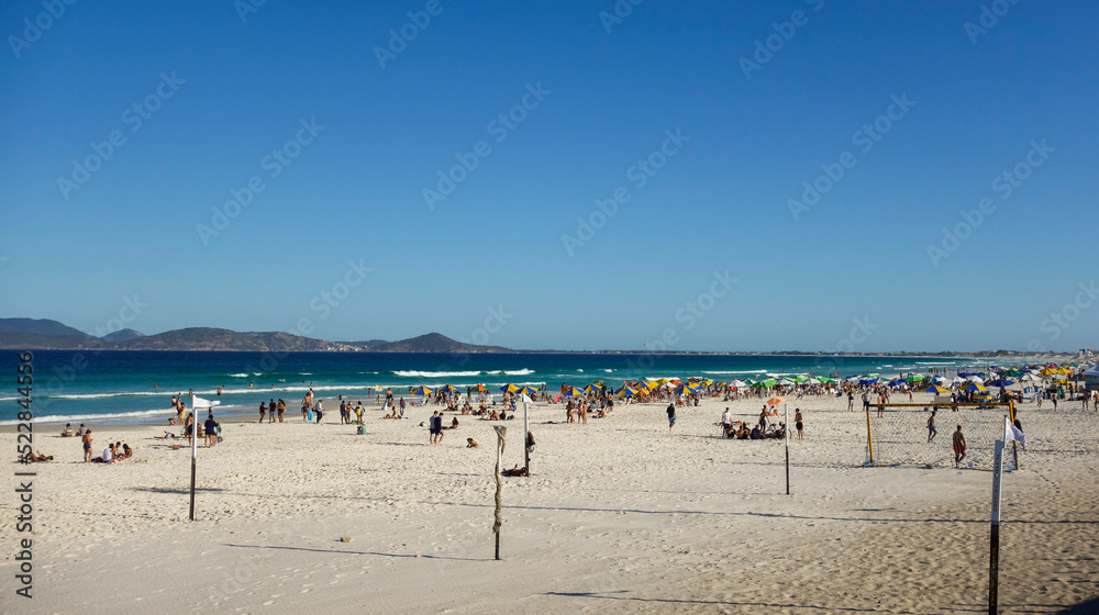 colorful umbrellas and tourists crowd the sand line at Praia do Forte in Cabo Frio, Rio de Janeiro, Brazil
