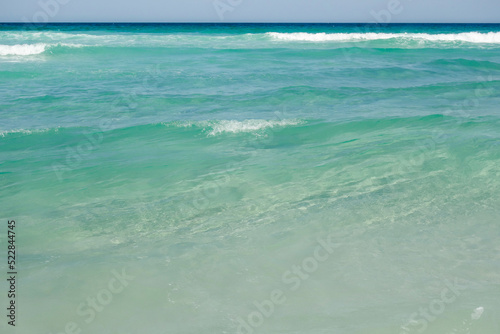 clear shallow sea water on tropical beach. Waves break on sand