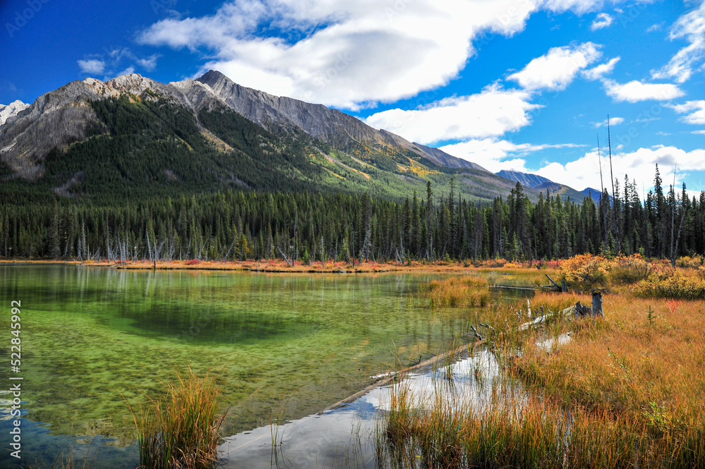 reflection of rocky mountains on small emerald green lake  fall season