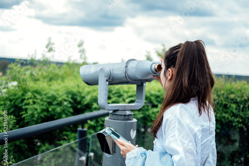 Travel, sightseeing. Young woman tourist looking in binoculars, telescope