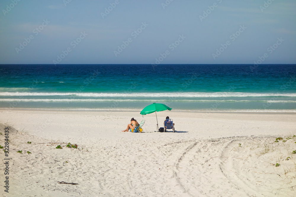 unidentified person under Beach Umbrella on the sand of Beautiful Clear Blue sea unidentified person under Beach Umbrella on the sand of Beautiful Clear Blue sea