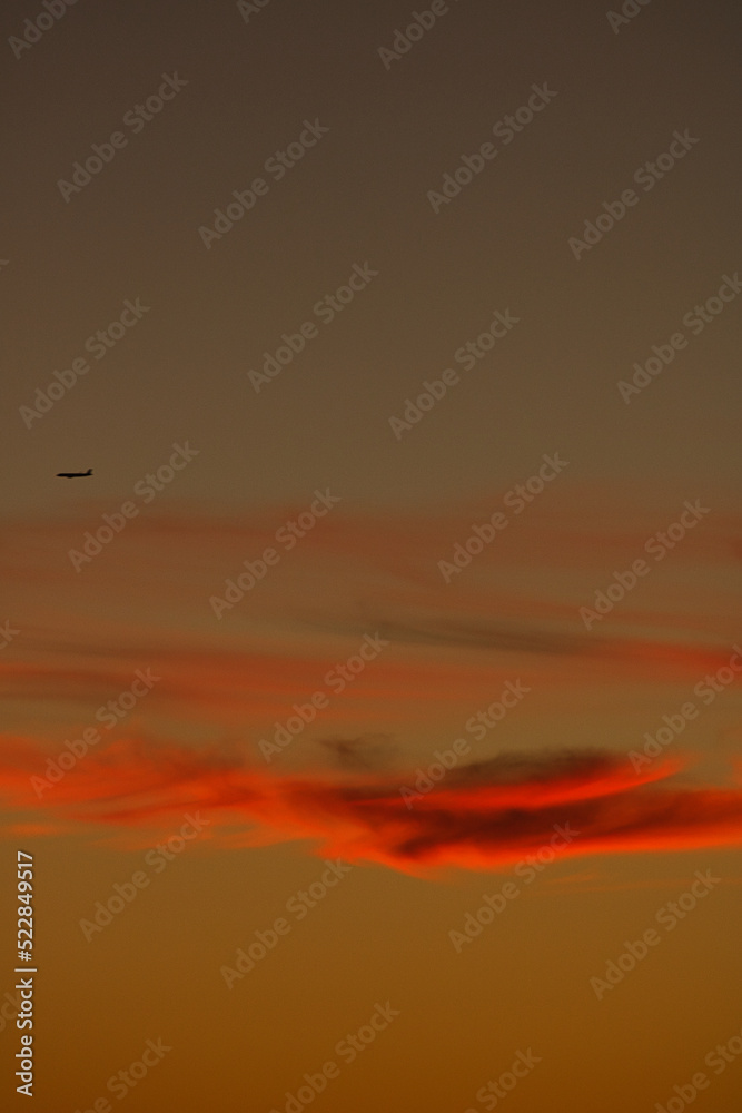 Plane silhouette over the clouds in sunset