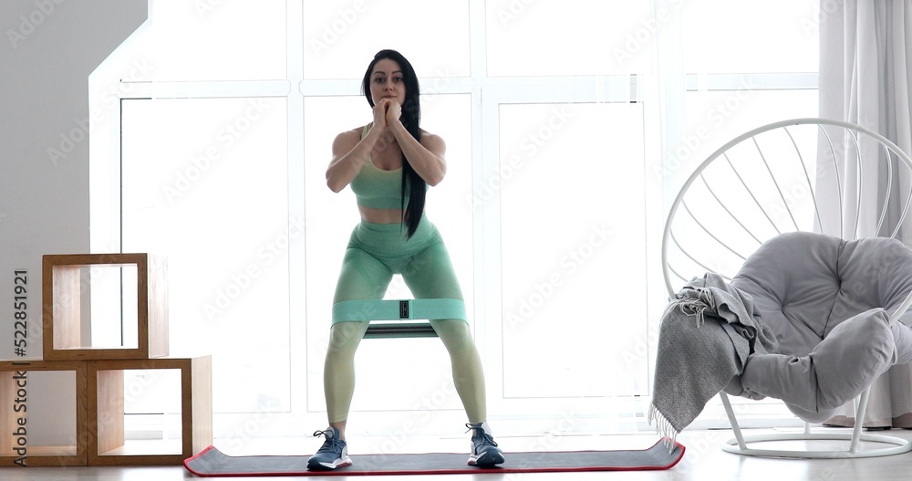 Woman doing exercises with resistance bands at home. Young woman exercising with an elastic band on the floor. Workout in home and quarantine concept. Woman doing exercises with resistance bands at home. Young woman exercising with an elastic band on the floor. Workout in home and quarantine concept.