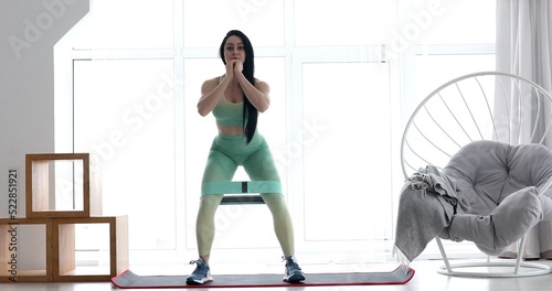 Woman doing exercises with resistance bands at home. Young woman exercising with an elastic band on the floor. Workout in home and quarantine concept.