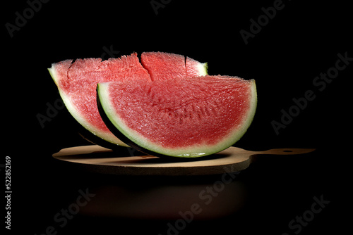 Two slices of pitted watermelon on a black background. Selective focus.