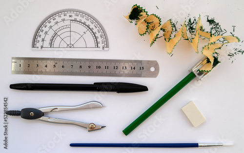 ruler, drawing brush, pencil with sharpener, protractor and compass on white background