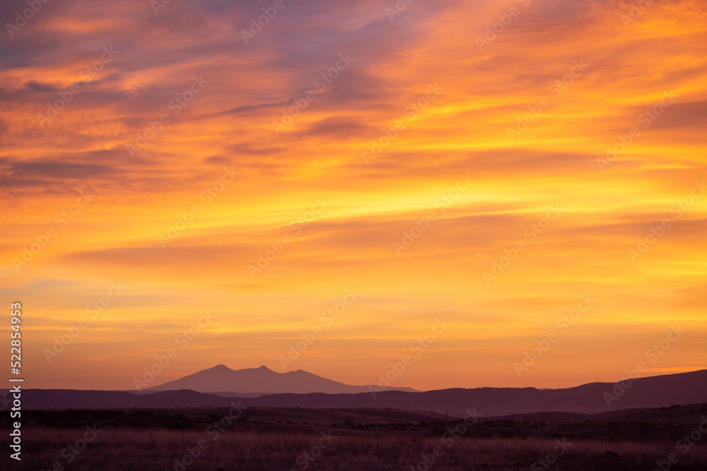 Colorful sunrise clouds over distant mountain range silhouette