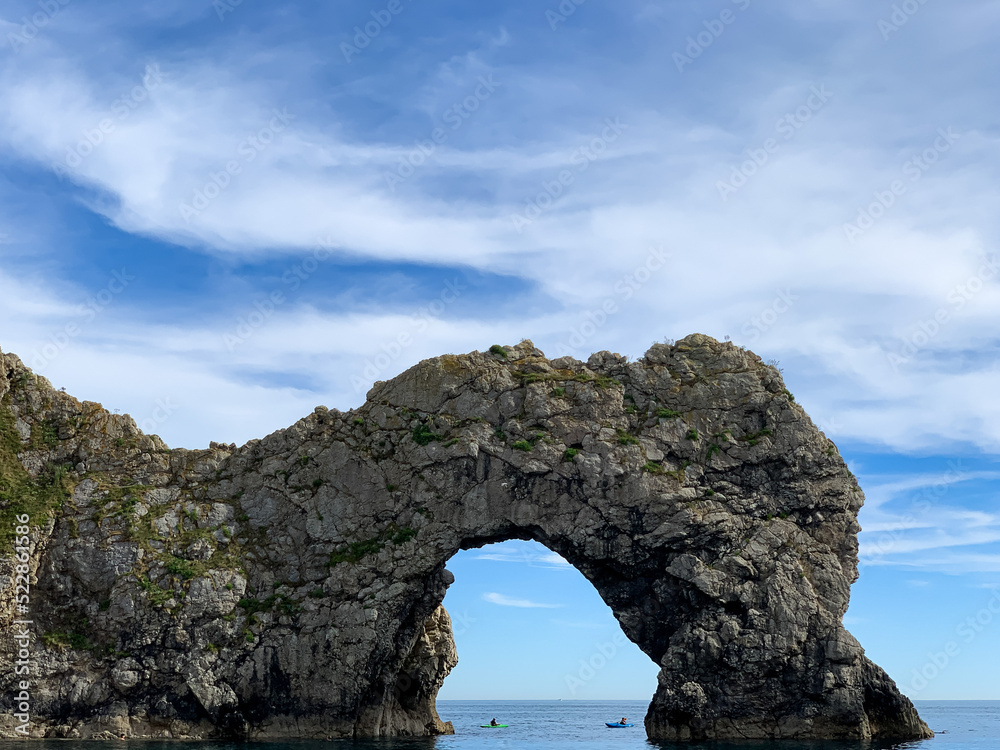 Hot summer day at Durdle Door limestone arch on the Jurassic Coast in Dorset. Natural landmark.Summer holidays England. Crowded beach, people are spending summer weekend in English seaside. Pure clean