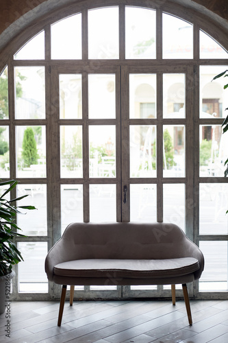 Sofa on the background of a window with a wooden frame and small glasses. Aesthetics and d cor