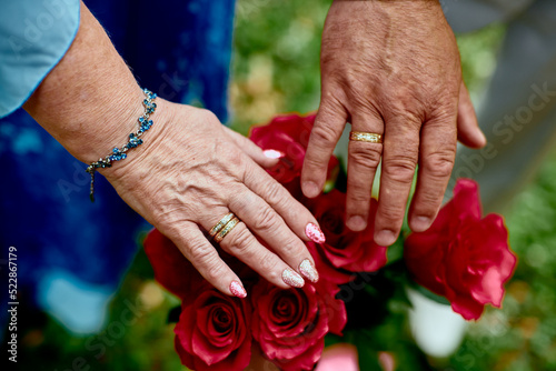 hands of old people with wedding rings over flowers in shallow depth of field