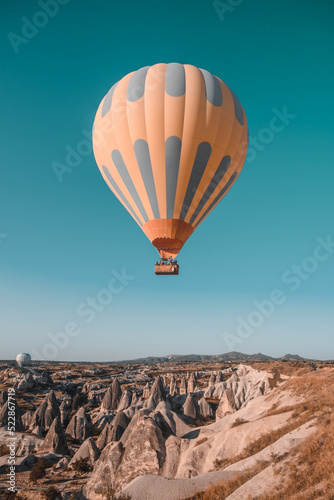 One orange hot air balloon in blue morning sky