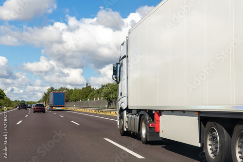 White blank modern delivery big shipment cargo commercial semi trailer truck moving fast on motorway road city urban suburb. Business distribution logistics service. Lorry driving highway sunny day