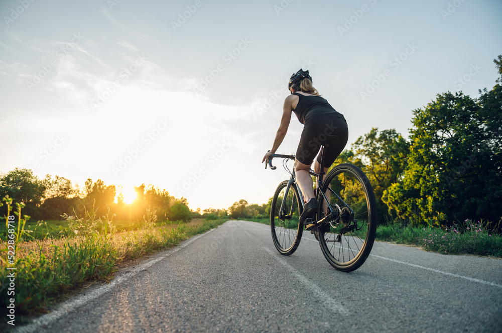 Sporty woman riding a bicycle in the nature while wearing a protective gear