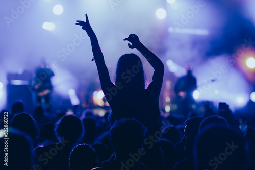 Silhouette of a woman with raised hands on a concert photo
