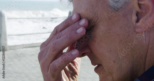 Stress, anxiety and worry with a senior man feeling negative, unhappy and sad. Retired male looking lonely, defeated and depressed while suffering with a headache, migraine or pressure outside