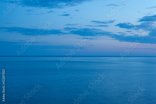 Background from the blue sea and the blue-blue sky with clouds and horizont line in the middle. Blue seascape for publication, poster, screensaver, wallpaper, postcard, cover, post. High quality photo