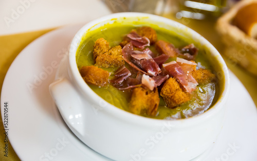 Cream soup of zucchini with croutons and sliced ham