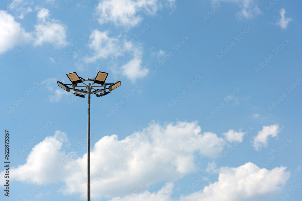 Tall metal lamppost with lamps in a circle against a blue cloudy sky - street lighting, LED lamps, energy saving Tall metal lamppost with lamps in a circle against a blue cloudy sky - street lighting, LED lamps, energy saving