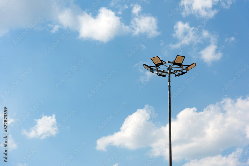 Tall metal lamppost with lamps in a circle against a blue cloudy sky - street lighting, LED lamps, energy saving Tall metal lamppost with lamps in a circle against a blue cloudy sky - street lighting, LED lamps, energy saving