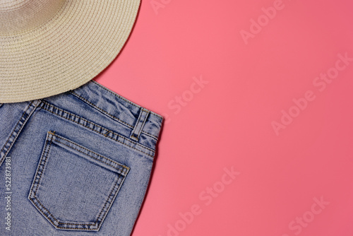 Women's straw hat and blue jeans on a roho background - preparation for vacation, top view, space for text photo