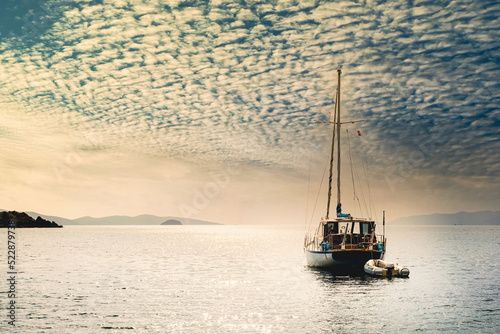 Sailboat Anchored on Calm Sea under Dramatic Cloudy Sky