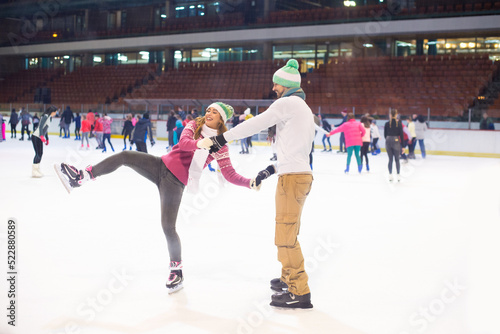 Young couple ice skating in the public ice skating rink in winter