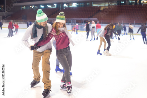 Young couple ice skating in the public ice skating rink in winter
