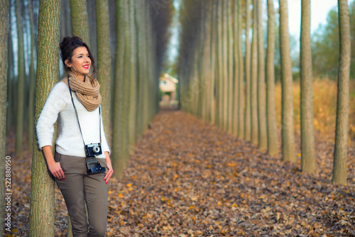 Young woman taking photos with analogue camera in  the autumn forest photo