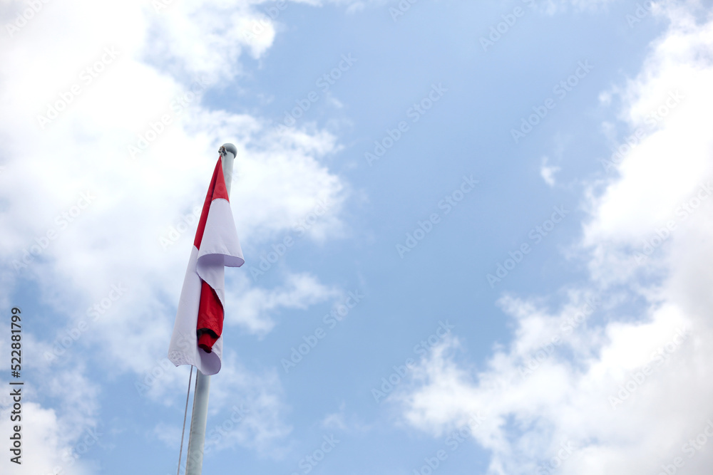Indonesian flag on pole against blue sky