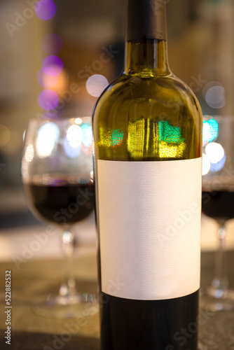 wine bottle with glass and party lights in background.