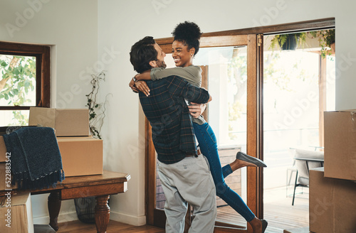 Homeowner couple celebrating, hugging and cheering in new home as real estate investors, buyers and owners. Fun interracial man and woman looking excited, happy and cheerful while embracing by boxes