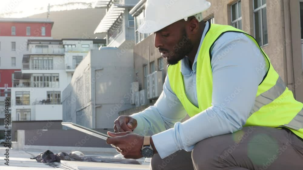 Professional male foreman or contractor inspecting a building and adding updates on a tablet. Young African American engineer checking on solar power, doing a routine checkup and performing a report