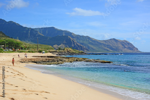 Uncrowded sandy and rocky coastline with mountains along the west side of Oahu Island in Hawaii