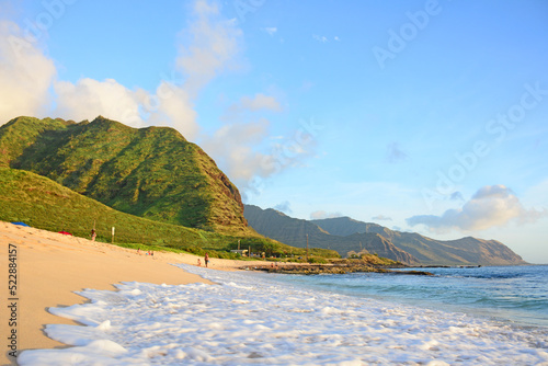Uncrowded beach coastline with mountains at sunset along the west side of Oahu Island in Hawaii