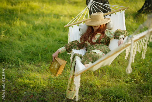 Woman with hat resting in comfortable hammock at green garden.