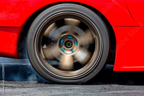 Fotografía Car wheel spinning wheel and smoking, Race car burning tire for warm up tire before competition, Racing car burns rubber preparation for race on speed track